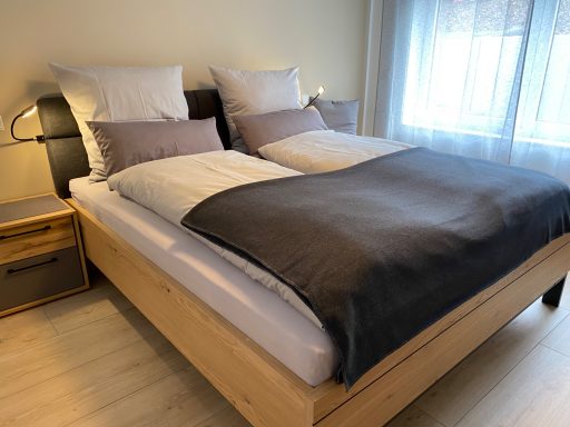 Doppelbett mit graßer Bettdecke und Kissen in modernem Schlafzimmer.