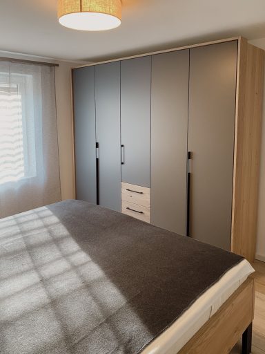 Schlafzimmer mit einem Bett und einem modernen, hellen Kleiderschrank.